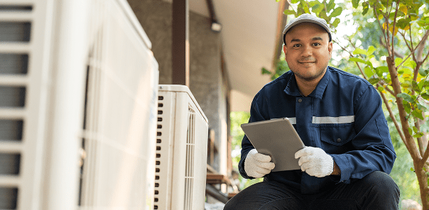 HVAC technician next to outdoor air conditioning unit